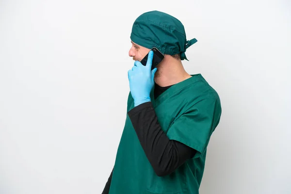 身穿绿色制服 被白色背景隔离的巴西外科医生与他人在手机上交谈 — 图库照片