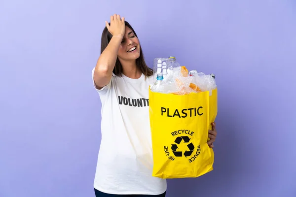 紫の背景に隔離されたリサイクルのためのペットボトルの袋を持っている若いブラジルの女性は何かを実現し 解決策を意図しています — ストック写真