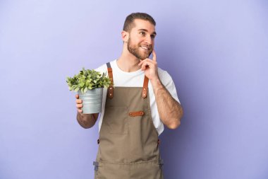 Bahçıvan Kafkasyalı bir adam sarı arka planda bir bitki tutuyor.