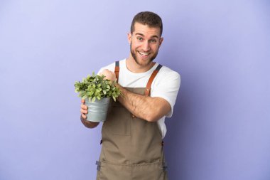 Bahçıvan Kafkasyalı adam sarı arka planda bir bitki tutuyor zaferi kutluyor.