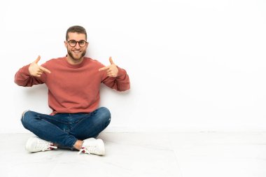Genç yakışıklı adam yerde oturmuş gururlu ve kendinden memnun.