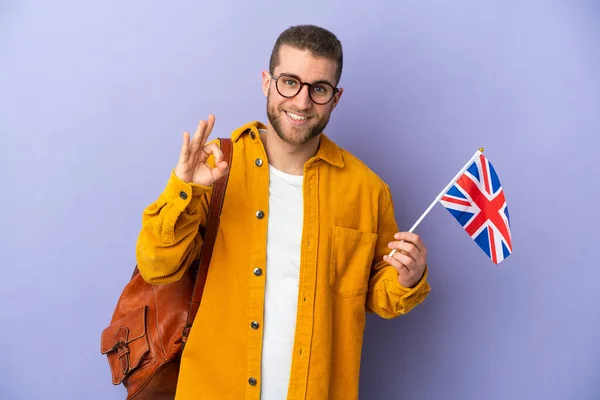 拿着英国国旗的年轻高加索人 背景为紫色 手指头上有可控标志 — 图库照片