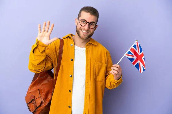 年轻的高加索人拿着一面英国国旗 背景是紫色的 手牵着手愉快地打招呼 — 图库照片