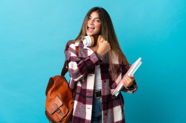 Mavi arka planda izole genç bayan bir zafer kutlaması yapıyor.