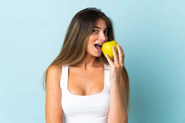 Mavi Arka Planda Izole Edilmiş Beyaz Bir Kadın Elma Yiyor — Stok fotoğraf