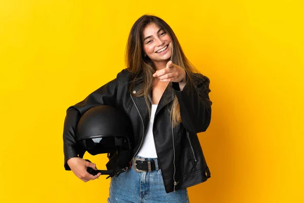 女性を保持していますオートバイヘルメットは幸せな表情で前を指して黄色の背景に隔離 — ストック写真