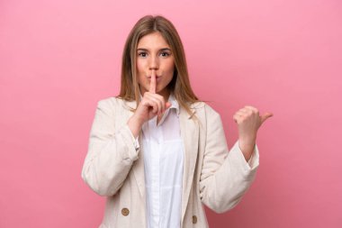 Pembe fırında izole edilmiş genç beyaz kadın yan tarafı gösteriyor ve sessiz hareketler yapıyor.