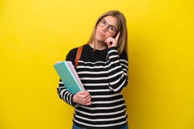 Sarı arka planda izole edilmiş genç bayan bir fikir düşünüyor.