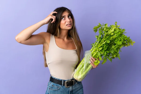 Young Woman Holding Celery Isolated Purple Background Having Doubts Confuse — Stock Photo, Image