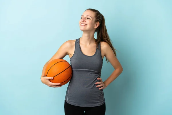 若いです女性遊びバスケットボール隔離された上の青の背景Posingとともに腕でヒップと笑顔 — ストック写真