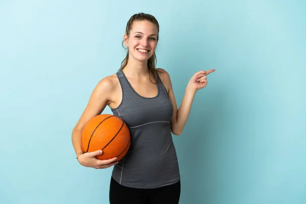 若いです女性プレーバスケットボールは 側に指を指す青の背景に隔離 — ストック写真