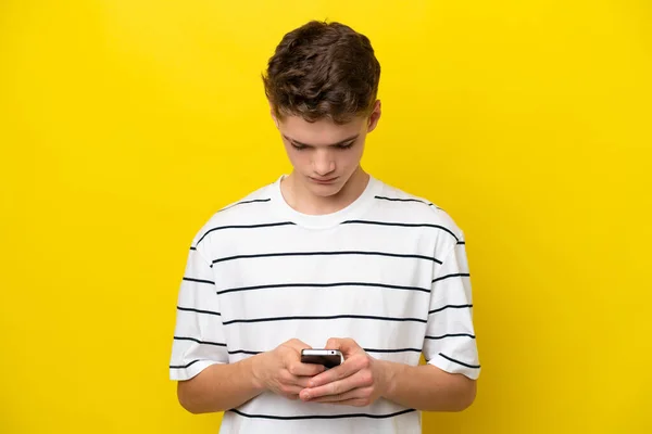 Teenager Russian Man Isolated Yellow Background Using Mobile Phone — Stock Photo, Image