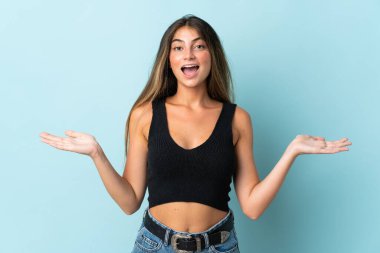 Yüzünde şok ifadesi olan mavi arka planda izole edilmiş beyaz bir kadın.