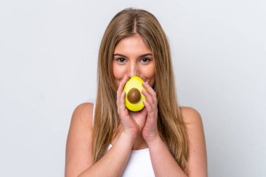Beyaz arka planda avakado tutan beyaz bir kadın. Portreyi kapat