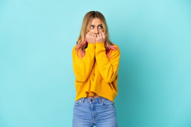 Soyutlanmış mavi arka planda genç bir kadın gergin ve korkmuş. El ele tutuşmaktan korkuyor.