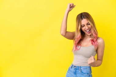 Sarı arka planda zafer kutlaması yapan genç bir kadın.