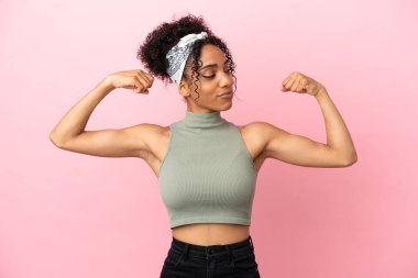 Pembe arka planda izole edilmiş genç Latin kadın güçlü bir jest yapıyor.