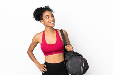 Spor çantalı genç Afro-Amerikan kadın mavi arka planda izole edilmiş bir şekilde bir fikir ararken...