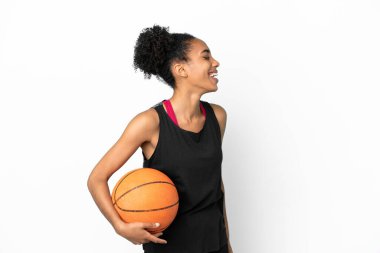 Genç basketbolcu Latin kadın, beyaz arka planda izole edilmiş. Yan pozisyonda gülüyor.