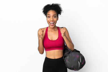Spor çantalı genç Afro-Amerikalı kadın mavi arka planda izole edilmiş galibiyeti kutluyor.