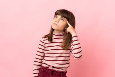 Little girl isolated on pink background making the gesture of madness putting finger on the head