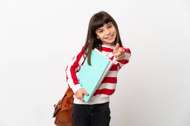 Beyaz arka planda izole edilmiş küçük kız mutlu bir ifadeyle ön tarafı işaret ediyor.