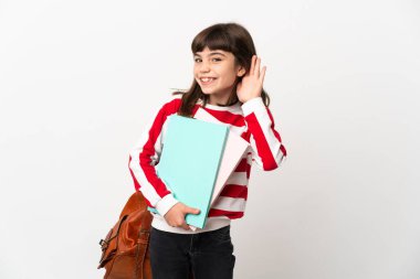 Beyaz arka planda izole edilmiş küçük kız elini kulağına koyarak bir şeyler dinliyor.