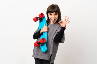 Beyaz arka planda küçük bir kız paten kayıyor ve tamam işareti yapıyor.