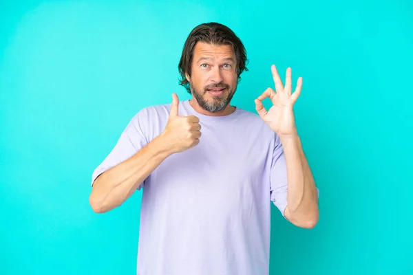 シニアオランダ人男隔離上の青背景ショーOk Signと親指アップジェスチャー — ストック写真