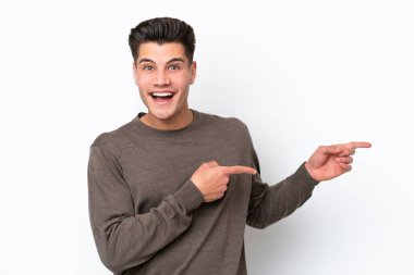 Beyaz fırında izole edilmiş yakışıklı beyaz adam şaşırmış ve işaret ediyor.