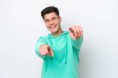 Beyaz fırında izole edilmiş yakışıklı beyaz adam mutlu bir ifadeyle ön tarafı işaret ediyor.