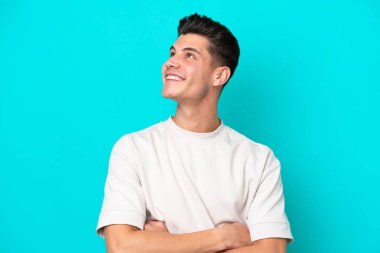 Genç, yakışıklı, beyaz bir adam mavi fırında izole edilmiş gülümserken yukarı bakıyor.