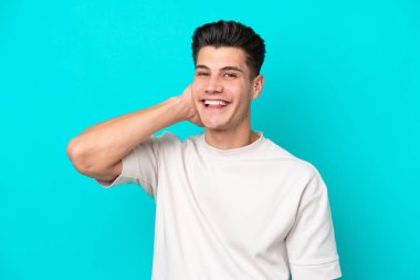 Genç, yakışıklı, beyaz bir adam mavi fırında yapayalnız gülüyor.