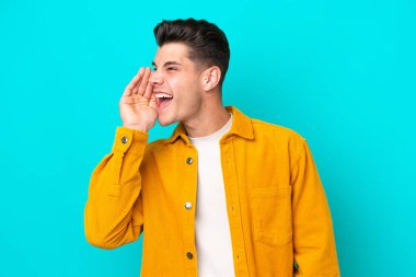 Genç, yakışıklı, beyaz bir adam mavi bir bakkalda izole edilmiş ve ağzı sonuna kadar açık bağırıyor.