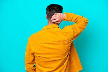 Genç, yakışıklı, beyaz bir adam arka tarafta mavi bir bakkalda izole edilmiş ve düşünüyor.