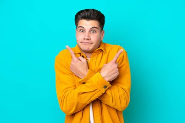 Genç, yakışıklı, beyaz bir adam mavi bir bakkalda izole edilmiş. Yan taraftakileri işaret ediyor.