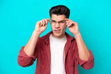 Genç yakışıklı beyaz adam mavi fırında tek başına, gözlüklü ve sinirli bir ifadeyle.