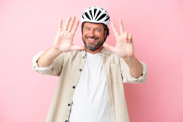 带自行车头盔的高个子男人 粉色背景 手指数到八 — 图库照片