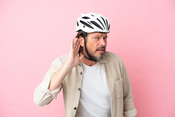 Homem Holandês Sênior Com Capacete Bicicleta Isolado Fundo Rosa Ouvindo — Fotografia de Stock