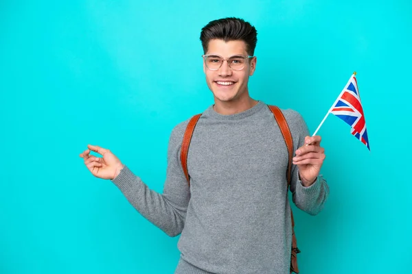 青い背景を指差したイギリス国旗を手にした若い白人男性が — ストック写真