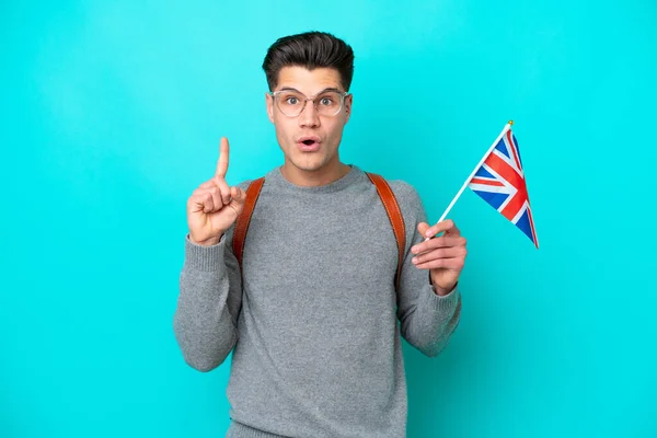 指を持ち上げながら解決策を実現しようと青色の背景に隔離された英国の旗を持つ若い白人男性 — ストック写真