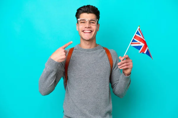 青い背景にイギリス国旗を掲げた若い白人男性が親指を立ててジェスチャー — ストック写真