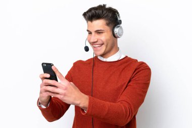 Tele pazarlamacı beyaz arka planda izole edilmiş kulaklıkla çalışan beyaz bir adam cep telefonuyla sohbet ediyor.