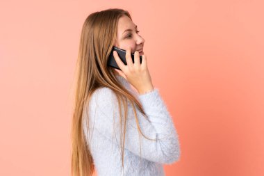 Pembe arka planda izole edilmiş genç Ukraynalı bir kız cep telefonuyla sohbet ediyor.