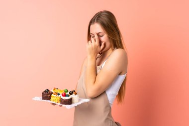 Ukraynalı aşçı pembe arka planda izole edilmiş bir kek tutuyor.