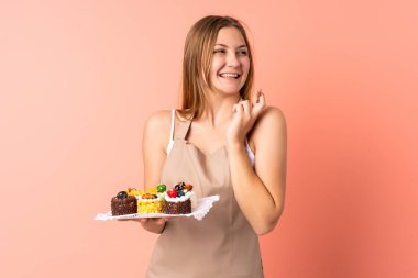 Ukraynalı aşçı pembe arka planda izole edilmiş bir kek tutuyor.