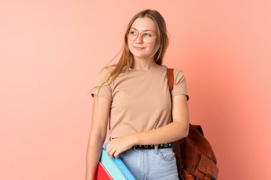 Genç Ukraynalı öğrenci kız pembe arka planda izole edilmiş duruyor ve yan tarafa bakıyor.