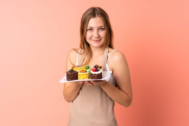 Pastacı Ukraynalı şef pembe arka planda izole edilmiş bir kek tutuyor.