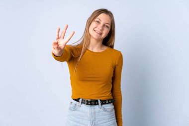 Genç Ukraynalı kız mavi arka planda izole edilmiş mutlu ve parmaklarıyla üçe kadar sayıyor.