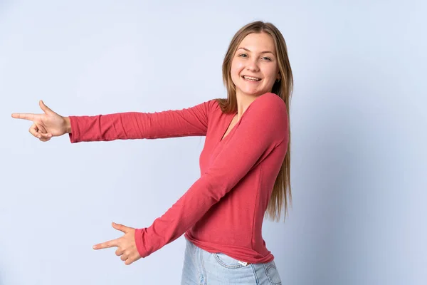 十代のウクライナの少女は 側に指を指して 製品を提示青い背景に隔離 — ストック写真